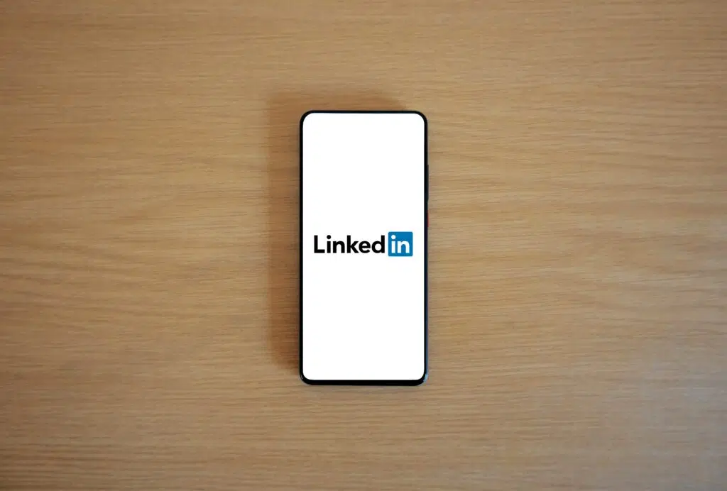 Smartphone displaying the LinkedIn app open, showcasing professional networking and content feed, with the headline 'Proven LinkedIn Marketing Strategies to Accelerate Business Growth.'