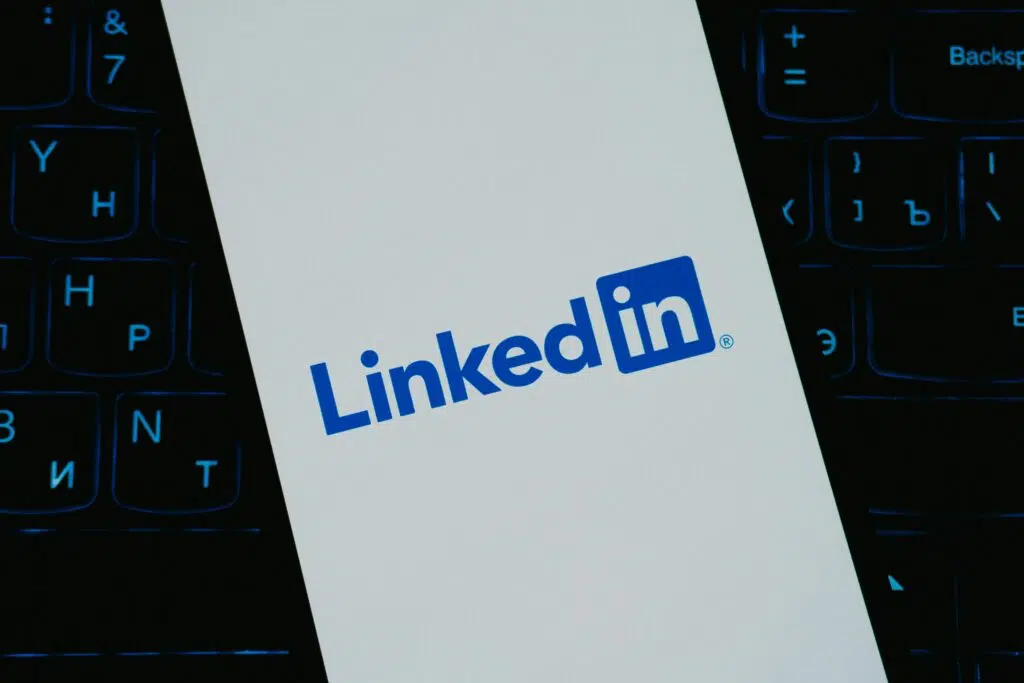 LinkedIn logo displayed on a smartphone screen over a computer keyboard, representing the LinkedIn Algorithm in 2025 and professional networking.